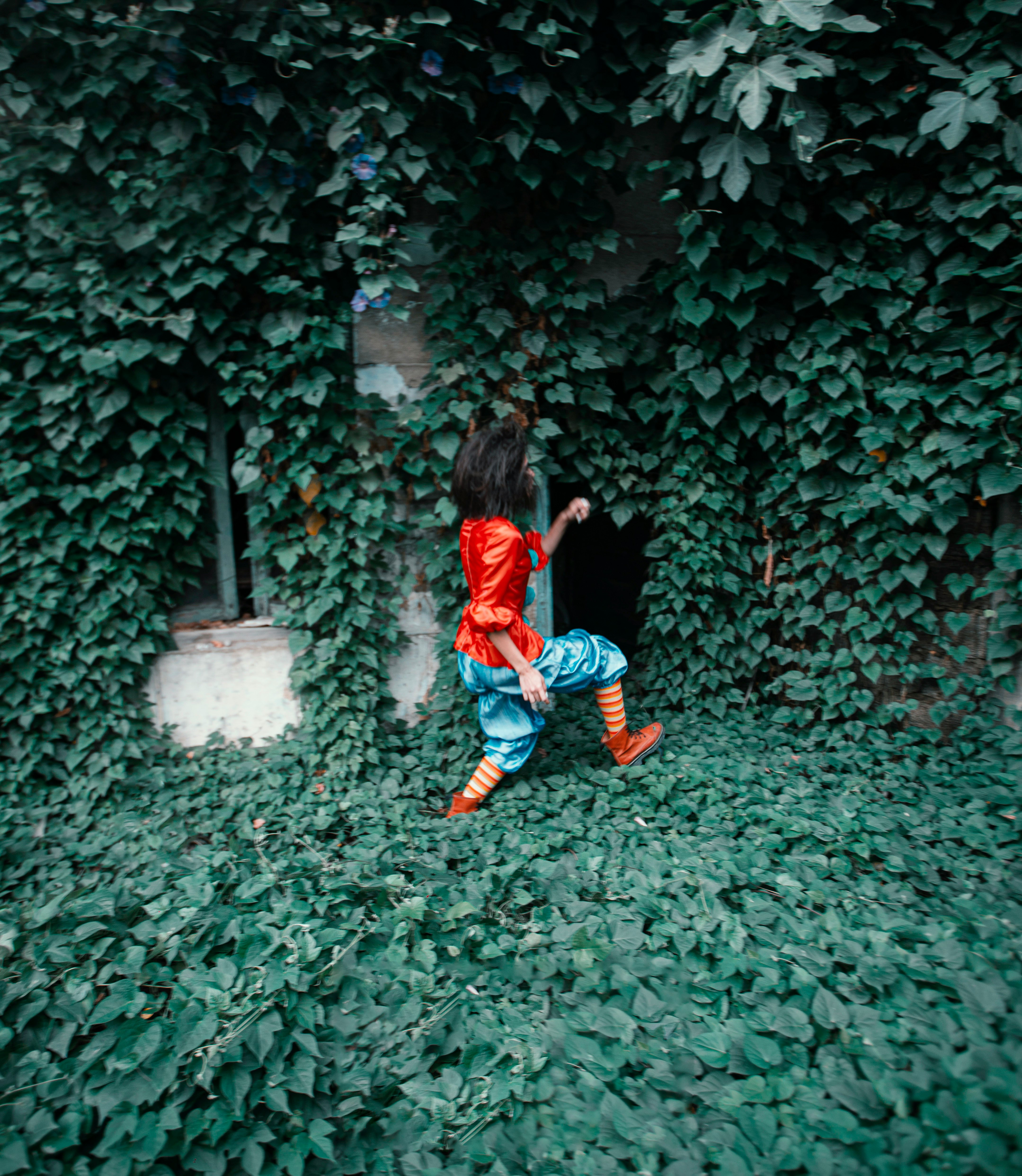 girl in red long sleeve shirt and blue denim jeans sitting on green grass during daytime